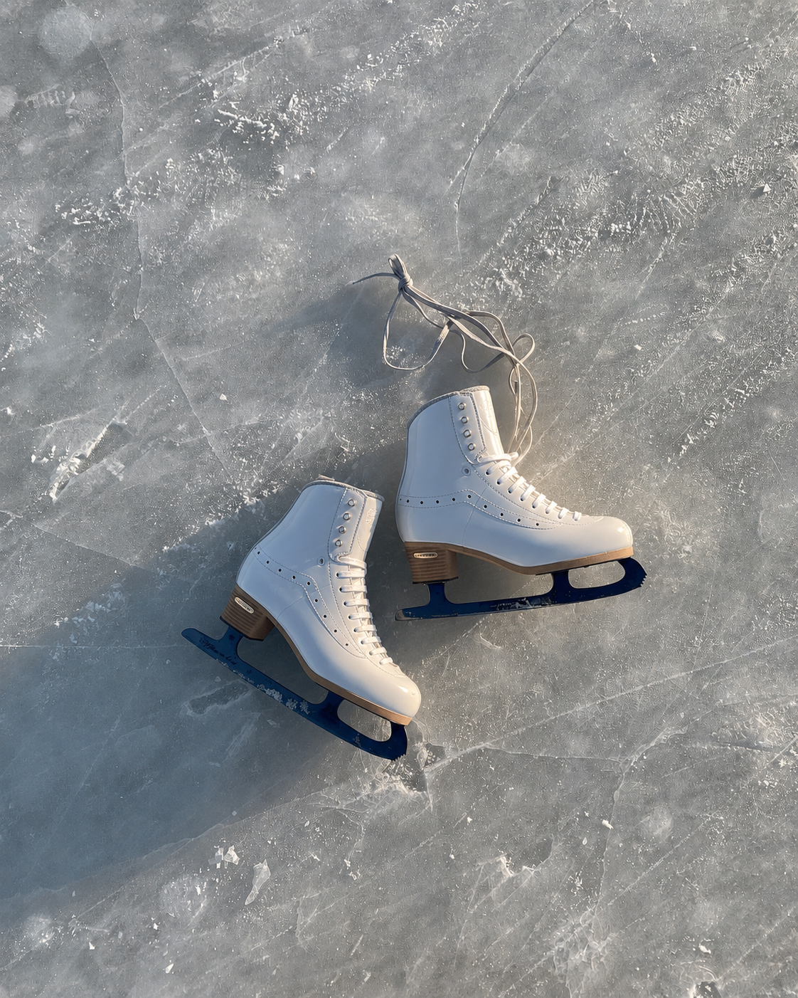 A pair of white figure skates resting on ice